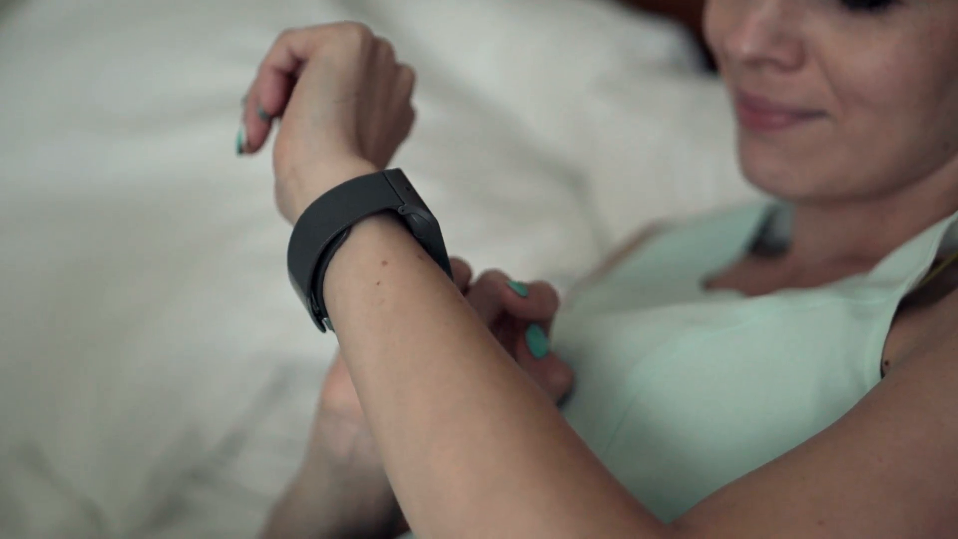 Una donna sta controllando uno smartwatch mentre è distesa in un letto.